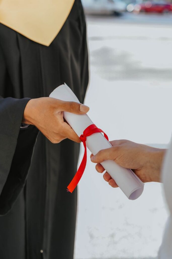 pexels photo 8093027 Hands exchanging a graduation diploma wrapped with red ribbon, symbolizing achievement.